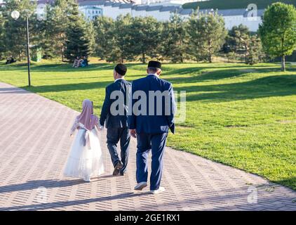 Mädchen in Kleid und wickeln Spaziergänge mit Großvater entlang Park Stockfoto