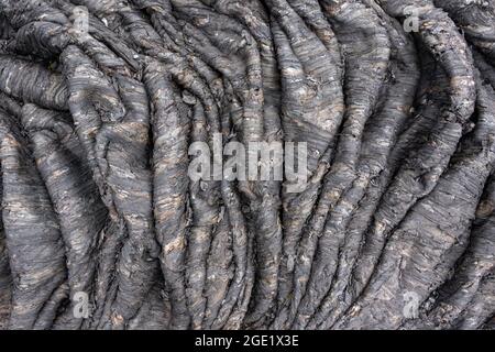 Natürlicher Hintergrund aus erstarrter vulkanischer Lava. Seillava ist das Ergebnis der Verlangsamung des Vorwärtsflusses und der Beschleunigung des Rückflusses. Zerknitterte vulkanische st Stockfoto