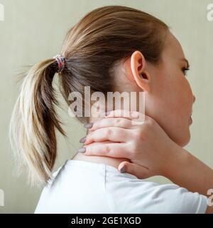 Nackenschulterschmerzen, Halswirbel. Frau hält Hals mit Schmerzen Halsmuskelkrampf von Hand. Erkrankung des Bewegungsapparates bei jungen Frauen Stockfoto