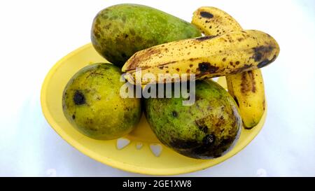 Drei reife Mangos und Bananen in einem Korb isoliert auf weißem Hintergrund Stockfoto