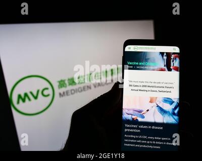 Person mit Mobiltelefon und Webseite des Biotech-Unternehmens Medigen Vaccine Biologics Corp. Auf dem Bildschirm mit Logo. Konzentrieren Sie sich auf die Mitte des Telefondisplays. Stockfoto