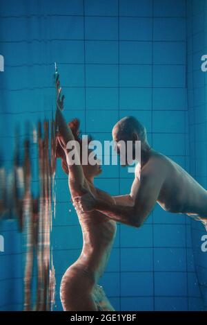 Unterwasserporträt des atletischen, sportlichen Tanzes und Yoga-Asanas-Paare (Mann und Frau) unter Wasser im Schwimmbad Stockfoto