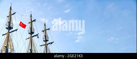 Die Masten des Schiffes mit der türkischen Flagge auf dem Hintergrund des blauen Himmels. Das Konzept von Reisen und Freiheit Stockfoto
