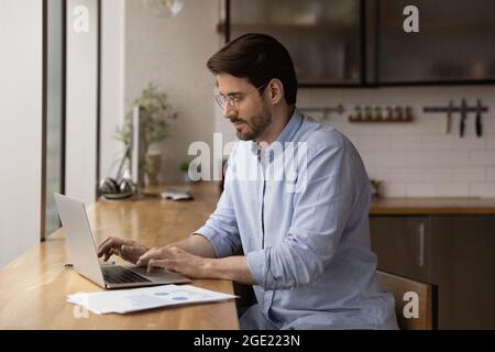 Seriöse männliche Unternehmer sitzen am Tisch arbeiten mit Laptop Stockfoto