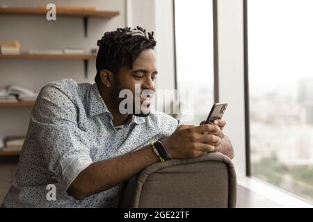 Afrikanischer Kerl machen Pause im modernen Büro mit Smartphone Stockfoto