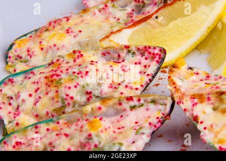 Kiwi-Muscheln, auch bekannt als grüne, grüne, riesige und Neuseeland, gebacken mit Käsesauce, Paprika, Parmesan, fliegender Fisch Rogen Tobiko. Stockfoto