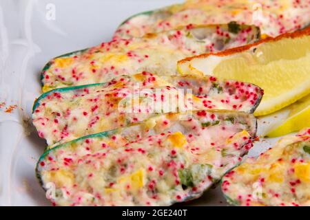 Kiwi-Muscheln, auch bekannt als grüne, grüne, riesige und Neuseeland, gebacken mit Käsesauce, Paprika, Parmesan, fliegender Fisch Rogen Tobiko. Stockfoto