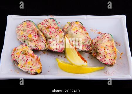 Kiwi-Muscheln, auch bekannt als grüne, grüne, riesige und Neuseeland, gebacken mit Käsesauce, Paprika, Parmesan, fliegender Fisch Rogen Tobiko. Stockfoto