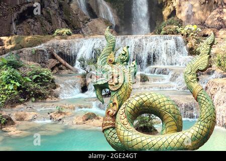 Alte Statue der mythischen asiatischen Naga Schlange und Tad Kuang Si Wasserfall im Wald in der Nähe von Luang Prabang, Laos, Asien Stockfoto