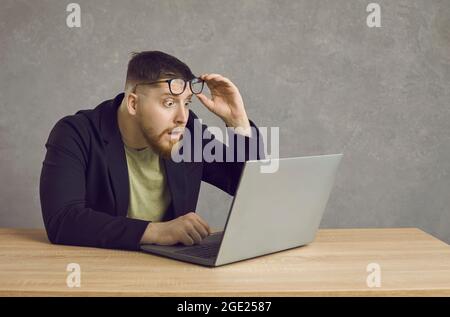 Der junge Mann ist schockiert, während er Telearbeit macht. Stockfoto