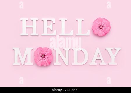 Happy Monday Worte auf schwarzem Briefbrett und Bouquet von hellen wilden Blumen in Zinn können Vase auf Tisch gegen blaue Holzwand. Konzept Hallo Montag. Stockfoto