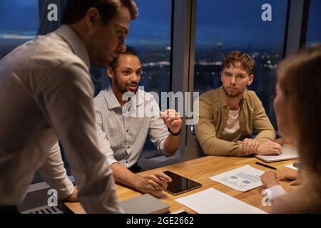 Eine Gruppe multiethnischer Kollegen arbeitet bis spät in die Nacht im modernen Büro Stockfoto