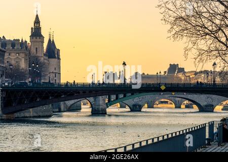 Paris, Frankreich - 1. März 2021: Wunderschöner Sonnenuntergang am Ufer der seine mit dem conciergerie-Denkmal im Hintergrund in Paris Stockfoto