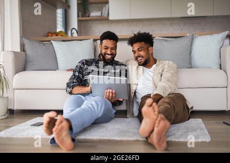 Junge Studentenbrüder in der Küche zuhause, mit Tablet und lachen. Stockfoto