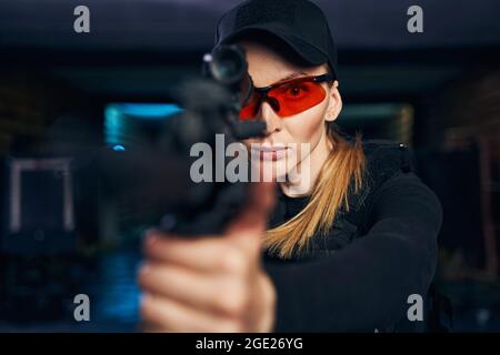 Erfahrene Scharfschützin in einer Schutzbrille, die aus einem Gewehr abfeuert Stockfoto