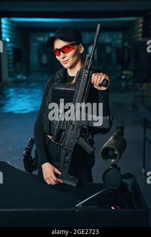 Junge Frau in einer kugelsicheren Weste mit einer Waffe Stockfoto