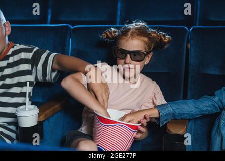 Glückliche kleine Kinder mit 3d-Brillen im Kino, beim Film und beim Popcorn. Stockfoto