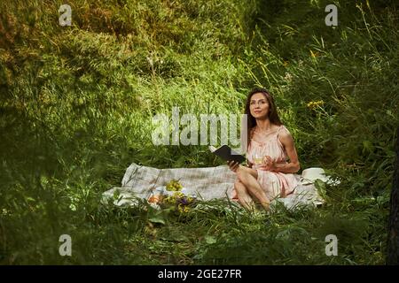 Attraktive Dame genießt ihr Picknick auf der Waldlichtung Stockfoto