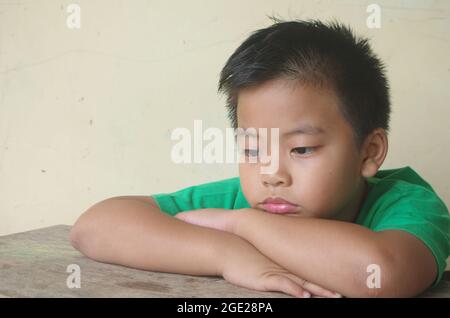 Einsamer Junge auf dem Tisch negative Kinder Emotion. Einsamkeit, Kind traurig Stockfoto