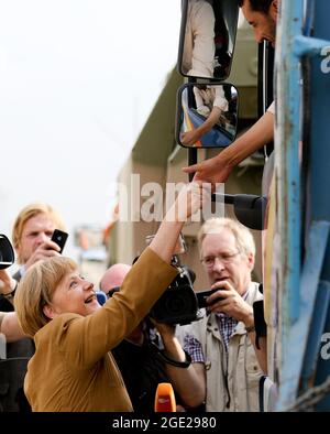 EINGEREICHT - 10. Mai 2013, Afghanistan, Kundus: Bundeskanzlerin Angela Merkel (l, CDU) besucht Bundeswehrsoldaten im Feldlager Kunduz und schüttelt sich mit einem lokalen Bundeswehrfahrer die Hände. Die Taliban haben die Hauptstadt Kabul viel schneller erreicht als erwartet. Dadurch wird die Evakuierung deutscher Bürger und lokaler afghanischer Truppen der Bundeswehr und der deutschen Ministerien schwieriger und gefährlicher. Der erste Evakuierungsflug wurde von einem US-Flugzeug durchgeführt. Der Betrieb soll mit Flugzeugen der Bundeswehr A400M fortgesetzt werden. In den nächsten Tagen sollen sie ein zentraler Teil eines 'Luftlifts' sein, der b Stockfoto