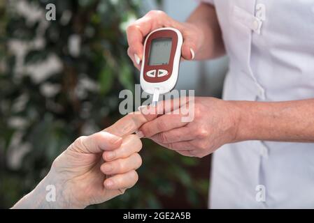 Krankenschwester, die den Blutzuckerspiegel überprüft Stockfoto