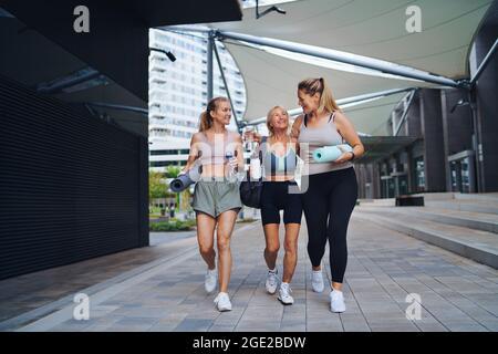 Eine Gruppe von jungen und alten Frauen, die nach dem Training in der Stadt im Freien spazieren und sich unterhalten. Stockfoto