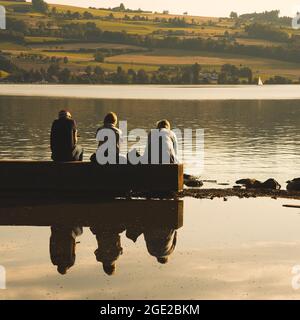 Nahaufnahme von drei Männern, die an einem sonnigen Tag am See in Sempach in der Schweiz sitzen Stockfoto