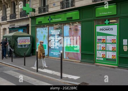 PARIS, FRANKREICH - 30. Jul 2021: Ein Mann in braunem Mantel und Gesichtsmask, der zu einer Apotheke in Paris, Frankreich, geht Stockfoto