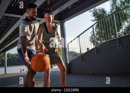 Mann und Frau Freunde spielen Basketball im Freien in der Stadt. Stockfoto