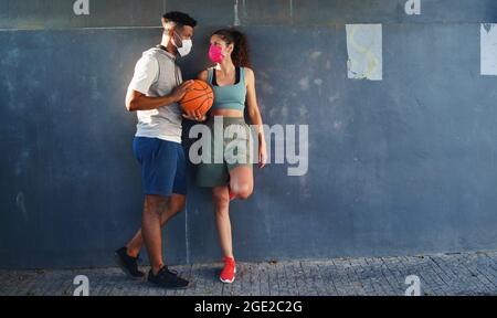 Mann und Frau, die mit Basketball befreundet sind, trainieren im Freien in der Stadt und sprechen. Coronavirus-Konzept. Stockfoto