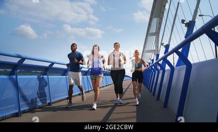 Eine Gruppe von jungen und alten Menschen, die draußen auf einer Brücke in der Stadt laufen. Stockfoto