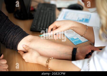 Ärztin oder Krankenschwester, die einem Patienten eine Spritze oder einen Impfstoff an die Hand gibt. Impfung und Prävention gegen Grippe oder Viruspandemie. Stockfoto