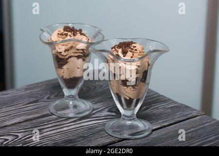 Dessert mit Rahm und Keksbröseln. Steht auf Kiefernbrettern. Nahaufnahme. Stockfoto