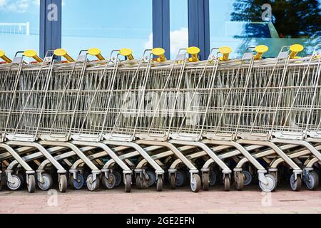 Viele leere Einkaufswagen auf dem Ladenparkplatz. Reihe von Einkaufswagen für Supermarktkäufer Stockfoto
