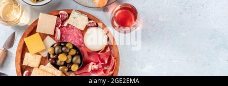 Wurstwaren und Käseplatte mit Weinpanorama, von oben mit einem Platz für Text aufgenommen. Italienische Antipasti für ein Restaurant-Menü Kopfzeile. Roséwein, Blau- und Ziegenkäse Stockfoto