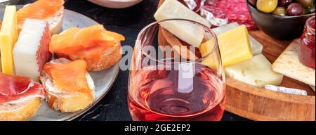 Rosenwein mit Käse, Lachsbrote und Olivenpanorama. Italienische Antipasti oder spanische Tapas-Panorama-Banner mit Weinglas Stockfoto