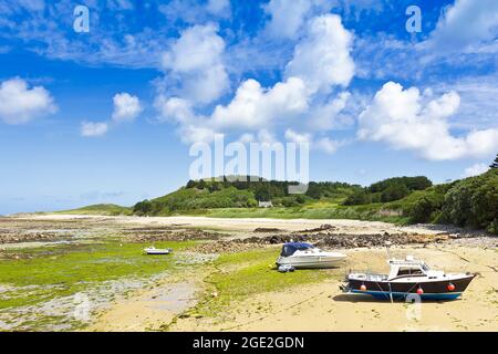 Herm, Kanalinseln, Großbritannien - 2. Juli 2016: Drei Boote, die an einem sonnigen Sommertag bei Ebbe am Fischerstrand an Land liegen. Stockfoto