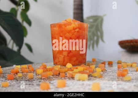 Rot und gelb tropische Früchte Papaya Baum in quadratische Würfel geschnitten im Essen und Trinken Album, Sommer Entspannung, in der Gartenecke auf dem Steintisch Stockfoto