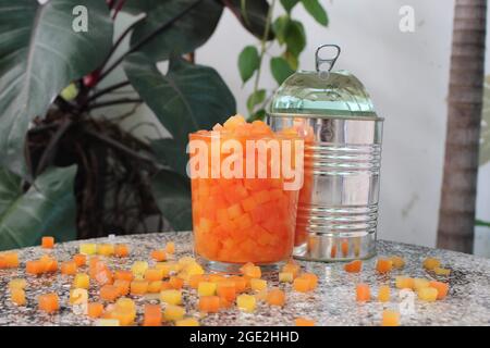 Rot und gelb tropische Früchte Papaya Baum in quadratische Würfel geschnitten im Essen und Trinken Album, Sommer Entspannung, in der Gartenecke auf dem Steintisch Stockfoto