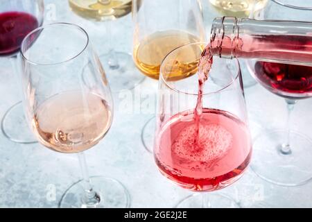 In ein Glas gießen Sie einen lebendigen Rosenwein. Weinprobe an einer Bar oder einer Party Stockfoto