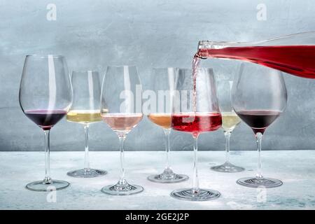 Bei einer Verkostung in ein Glas gegossen, mit Weiß- und Rotwein in verschiedenen Farben. Weinprobe Stockfoto