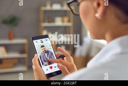 Alleinstehende Frau hält Smartphone und geben gerne Foto von jungen Mann auf Online-Dating-App Stockfoto