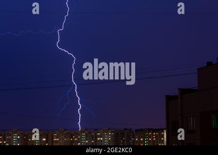 Blitzschlag in der Stadt Moskau, Russland. Blitz in der Abendstadt über Wohngebäuden. Dunkelblauer Himmel. Stockfoto