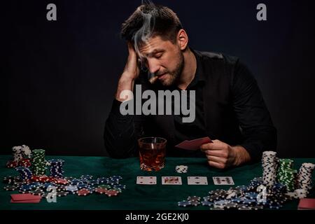 Bärtiger Casino Spieler Mann, der Poker auf dem grünen Tisch spielt Stockfoto