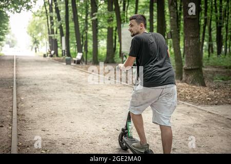 Junger Mann auf einem Elektroroller, ökologisches Transportkonzept. Stockfoto