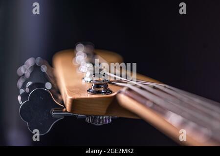 Detail eines Stimmpfostens auf dem hölzernen Kopfstock einer E-Bass-Gitarre. Stockfoto