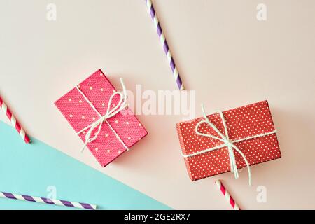 Zwei Geschenkschachteln, eingewickelt in Papier mit roten und violetten Punkten auf rosa Hintergrund. Stockfoto