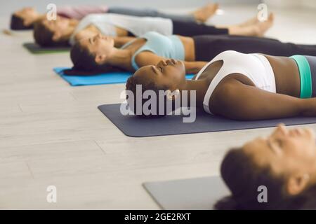 Frauen, die am Ende eines Yoga-Gruppenkursen im Fitnessstudio auf dem Boden in Shavasana liegen Stockfoto