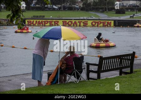 Urlauber trotzen den Elementen am Goodrington North Beach in Paignton, Devon, der von Gewitterschauern getroffen wurde und einige Touristen dazu zwingt, für Deckung zu laufen, Großbritannien. Stockfoto