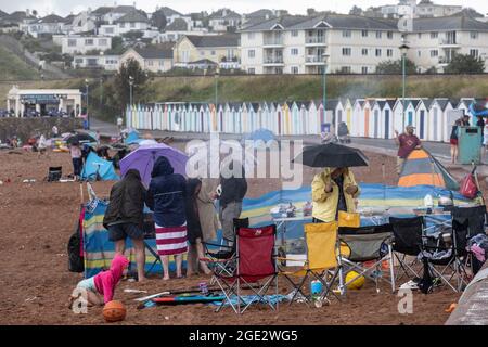 Urlauber trotzen den Elementen am Goodrington North Beach in Paignton, Devon, der von Gewitterschauern getroffen wurde und einige Touristen dazu zwingt, für Deckung zu laufen, Großbritannien. Stockfoto